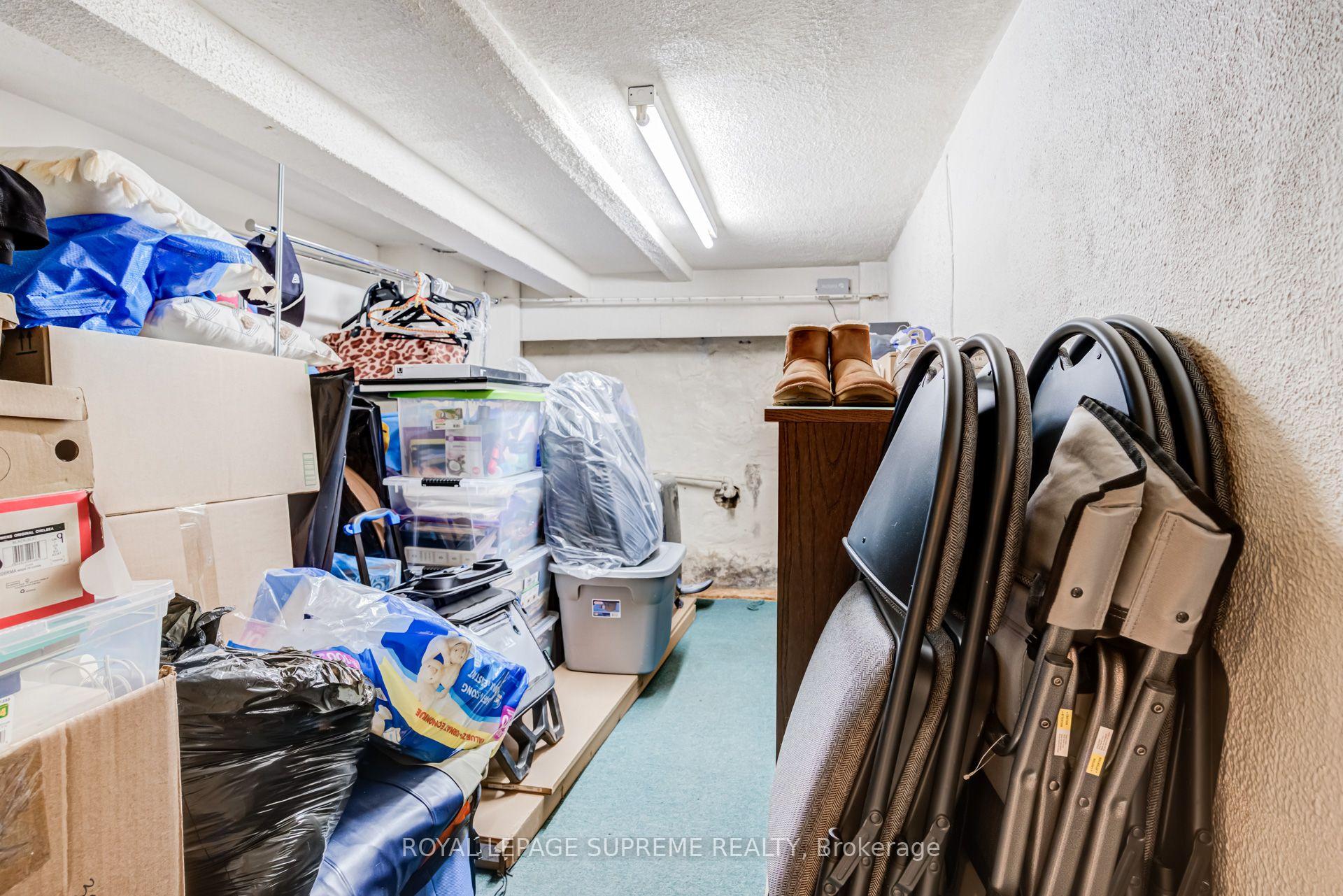 Crowded storage room filled with boxes, plastic bins, and folded chairs.