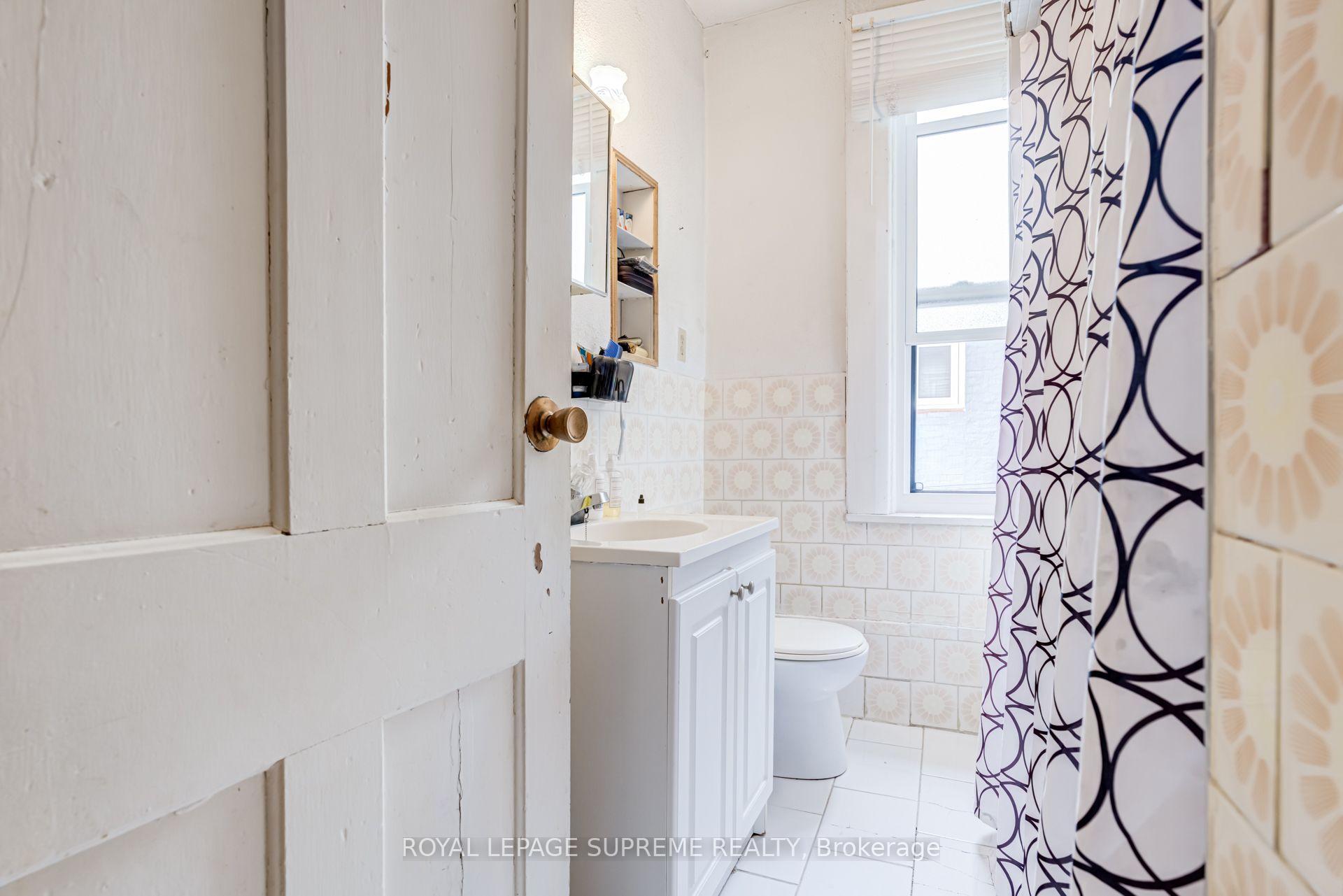 Bathroom with a white vanity, patterned tile, and navy geometric shower curtain.