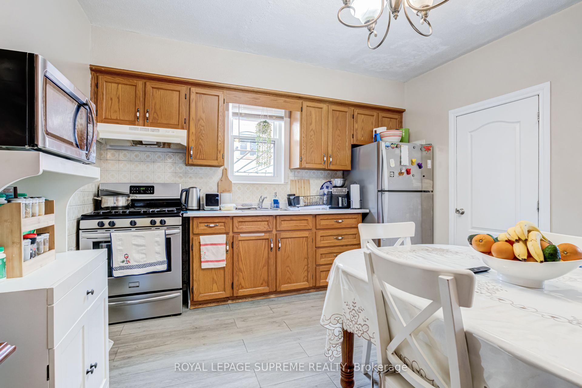 Kitchen with wood cabinets and stainless steel appliances, adjoining a dining table with a bowl of fruit.