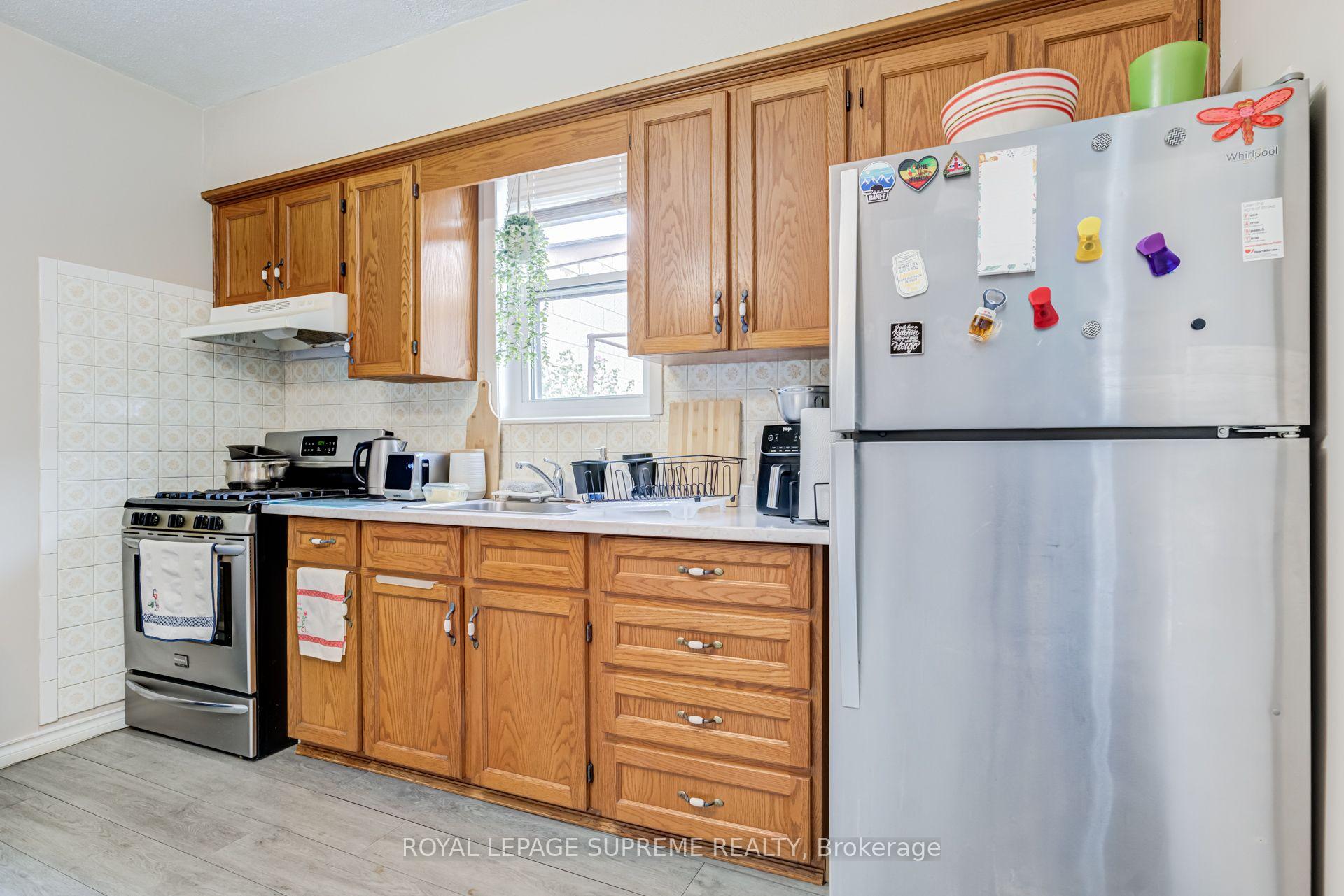 Kitchen with oak cabinets, stainless steel appliances, tiled backsplash, and a window above the sink.