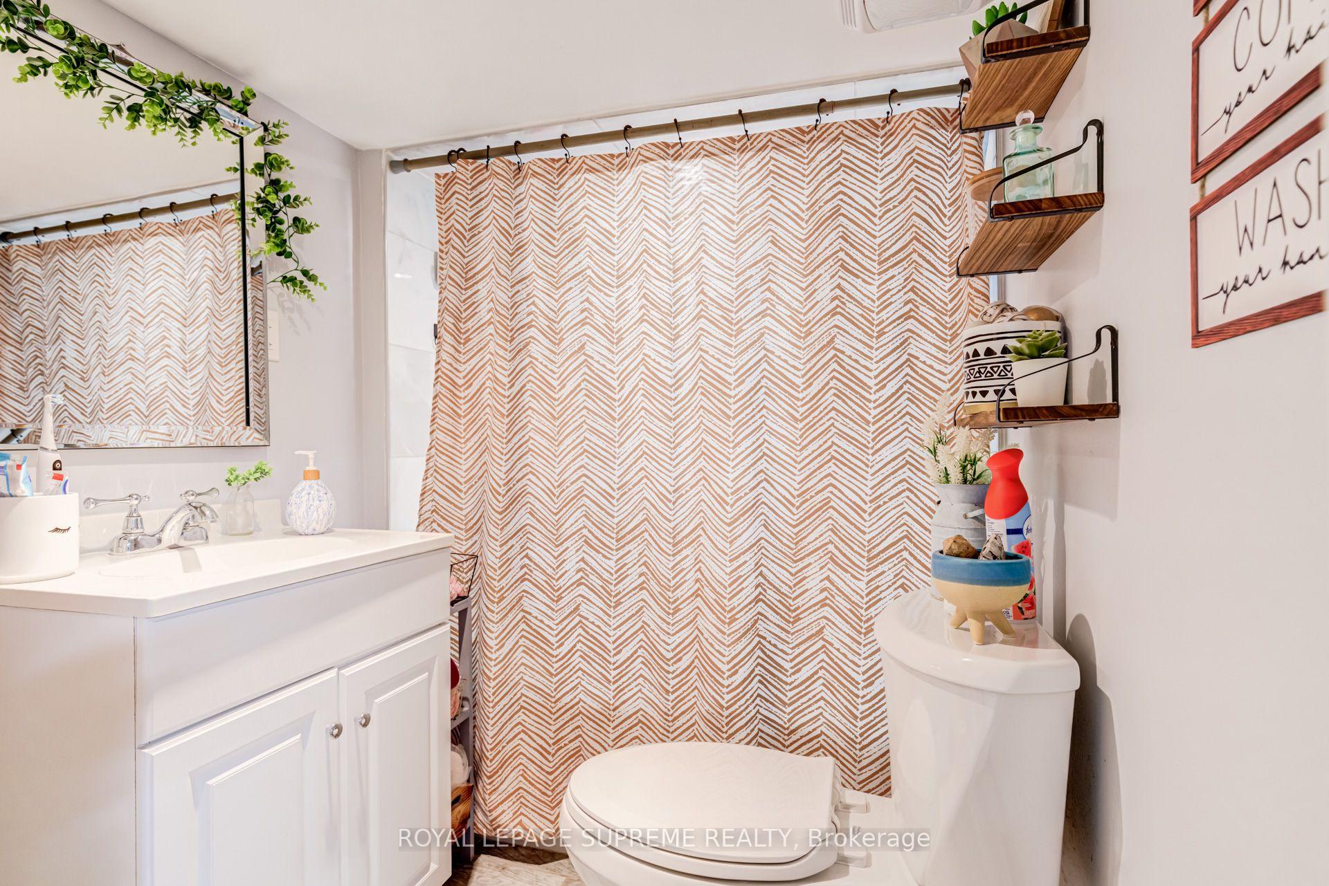 Bathroom with a white vanity, toilet, and tan-and-white chevron shower curtain.