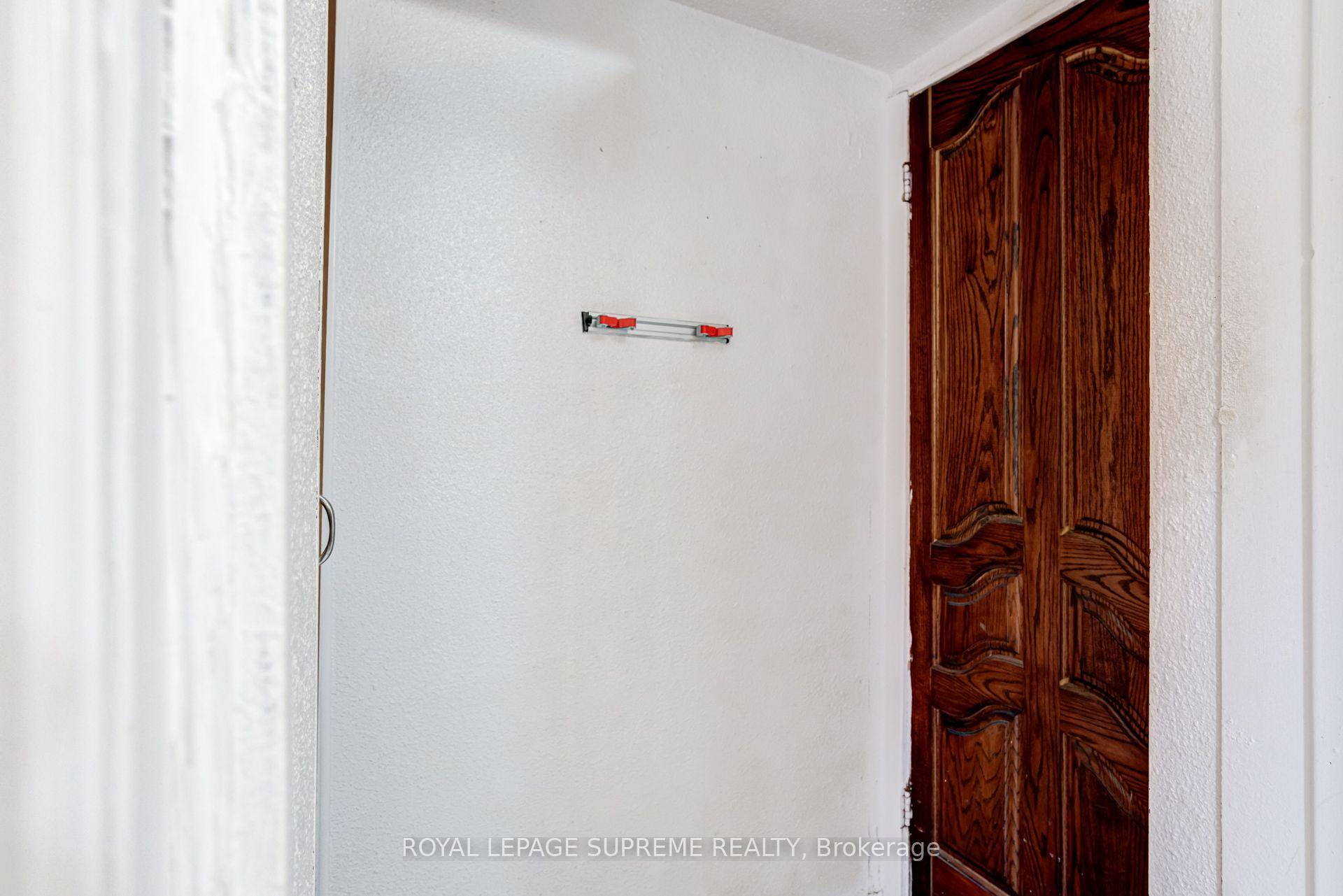 White interior wall and ornate dark wooden door with a small metal rail.