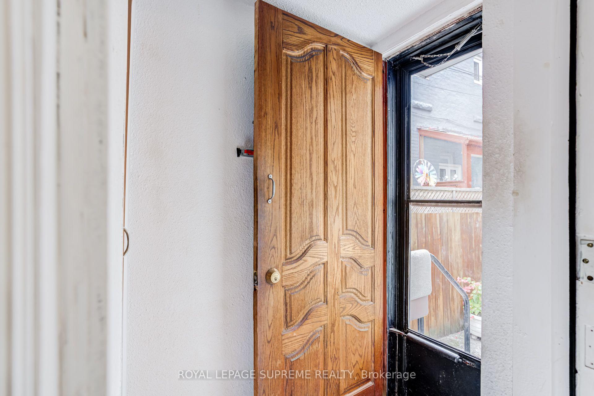 Open carved wooden front door beside a black-framed glass storm door.