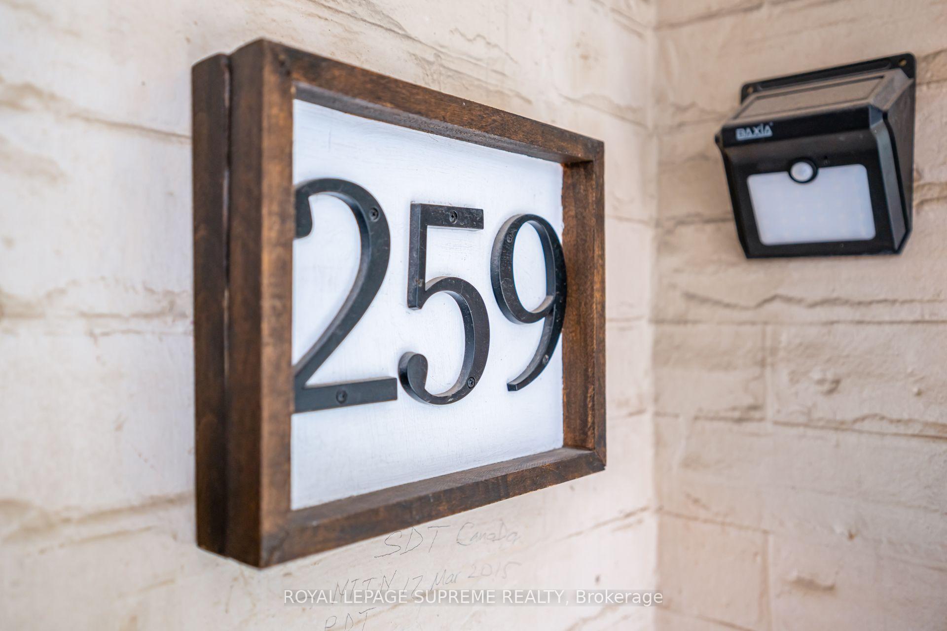 House number 259 on a framed plaque beside a motion-sensor light.
