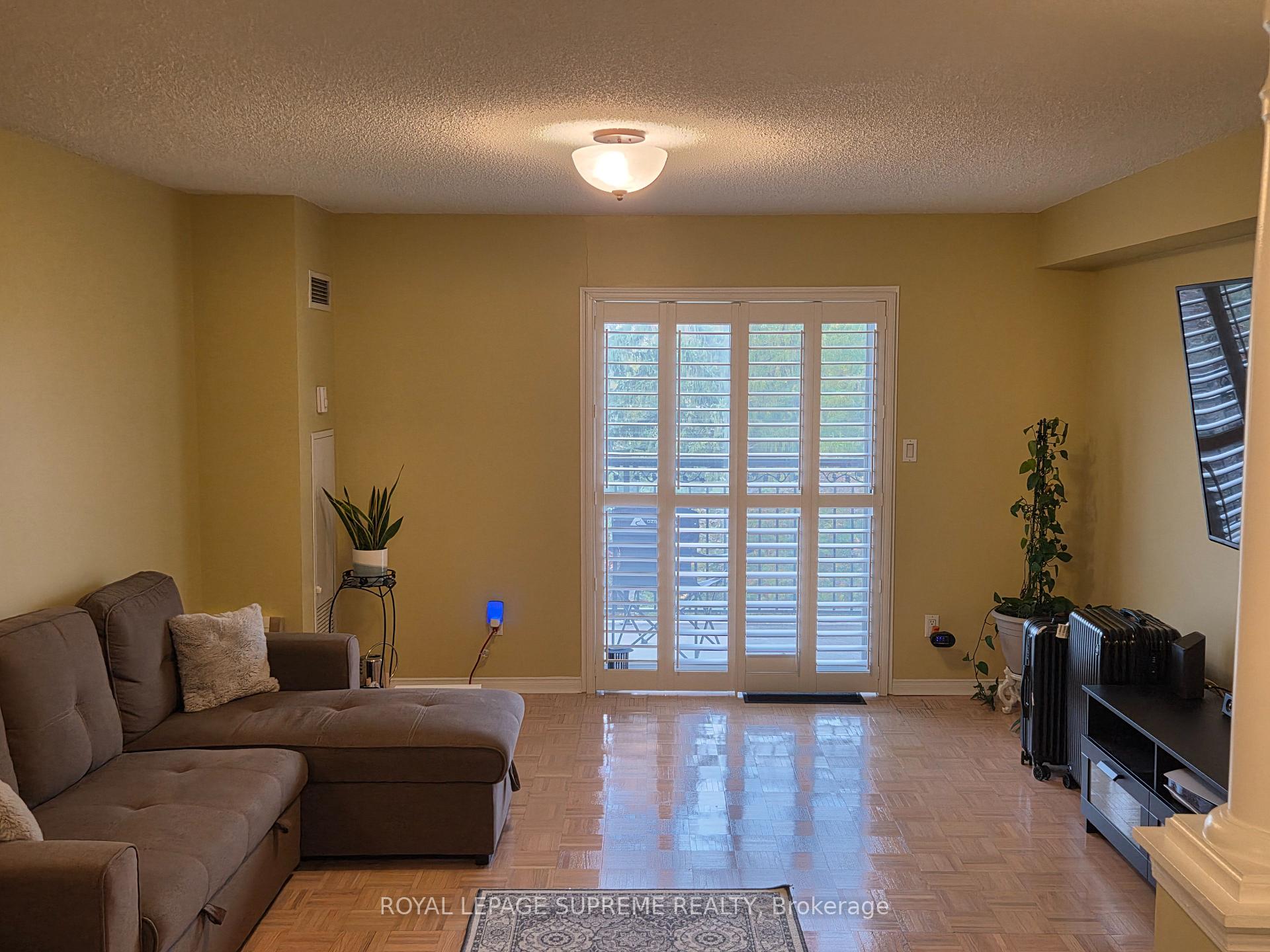 Living room with a brown sectional sofa and shuttered glass doors opening onto a balcony.