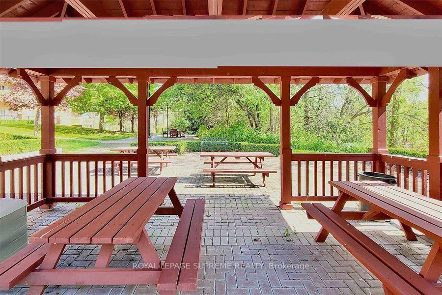 Red wooden pavilion with picnic tables overlooking landscaped grounds.