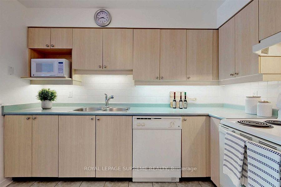 Kitchen with light wood cabinetry, pale aqua counters, and a built-in microwave.
