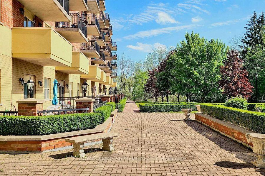 Condominium courtyard with brick paving, clipped hedges, benches, and balconies.