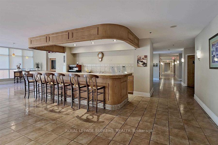 Building amenity kitchen with a long wood counter, bar stools, and a hallway to the right.