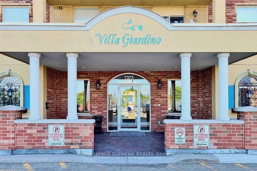 Villa Giardino building entrance at 7373, with a brick facade, arched canopy, and white columns.