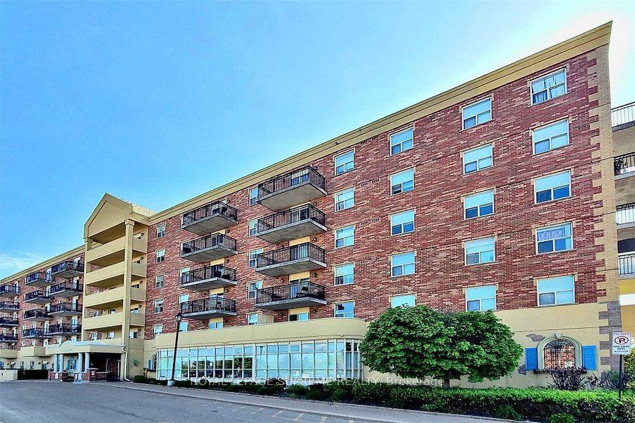 Red-brick apartment building with balconies and a beige entrance structure.