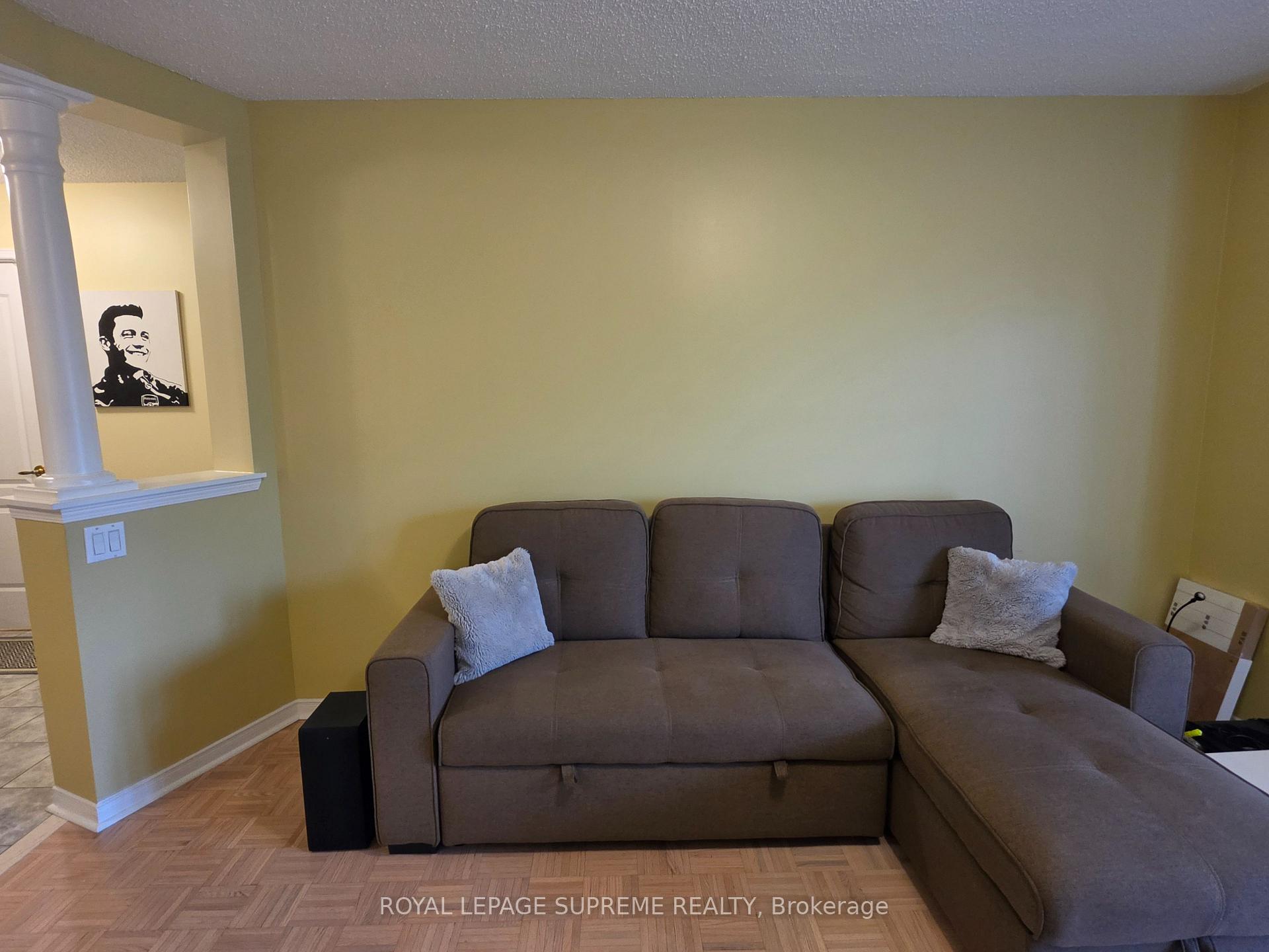 Living room with a gray sectional sofa, pale yellow walls, and parquet flooring.