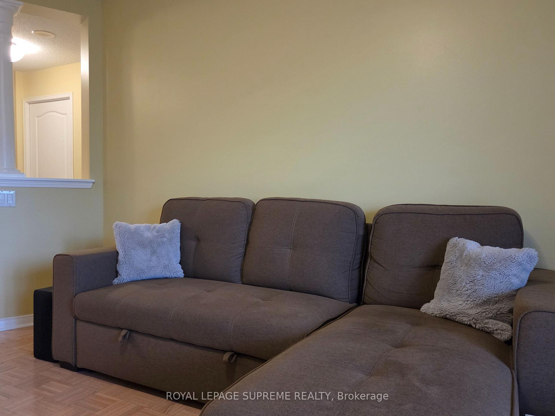 Living room with a dark gray sectional sofa, light throw pillows, and hardwood flooring.