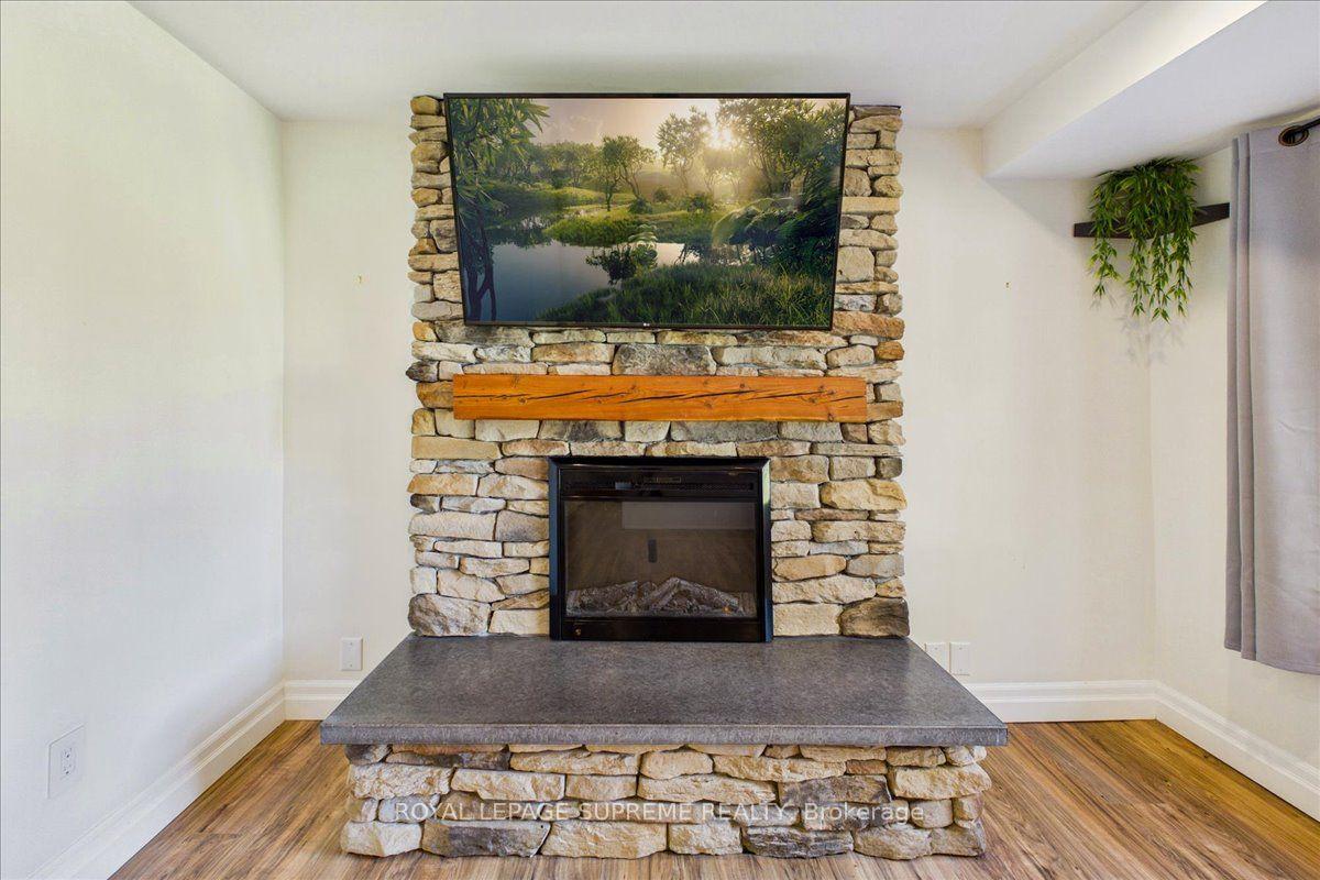 Stone fireplace with a wide gray hearth, wooden mantel and television mounted above.