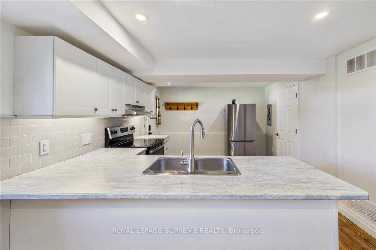 Kitchen with white cabinetry, subway tile, and a wide peninsula with a double sink.