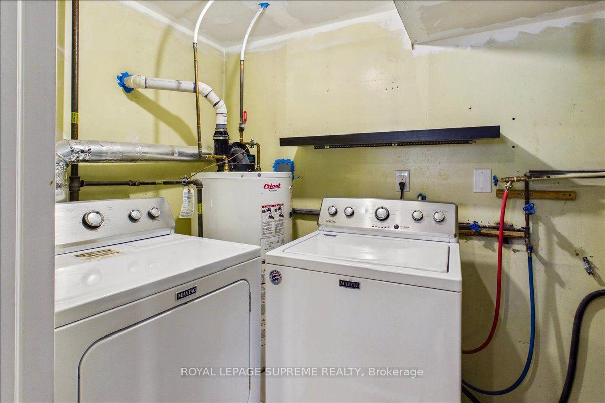Basement laundry room with a Maytag dryer, top-loading washer, exposed plumbing, and water heater.