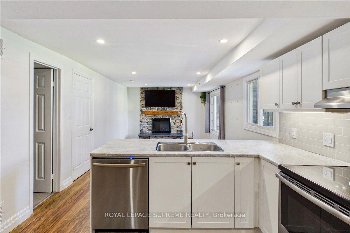 Lower-level kitchen with a large double-sink island and stone fireplace beyond.