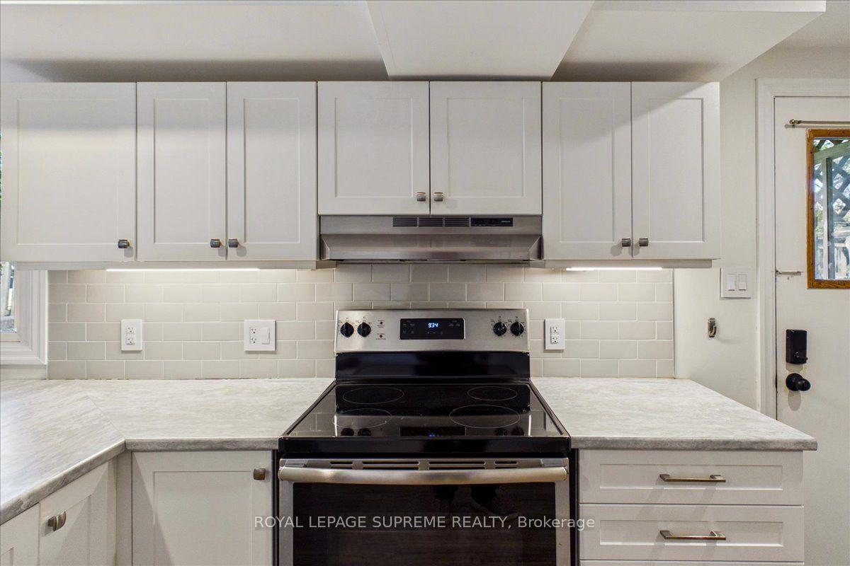 Kitchen with white cabinets, pale subway-tile backsplash, and a black electric range.