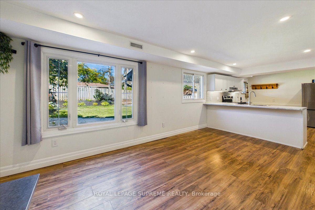 Open kitchen with a white peninsula and large window overlooking a fenced yard.