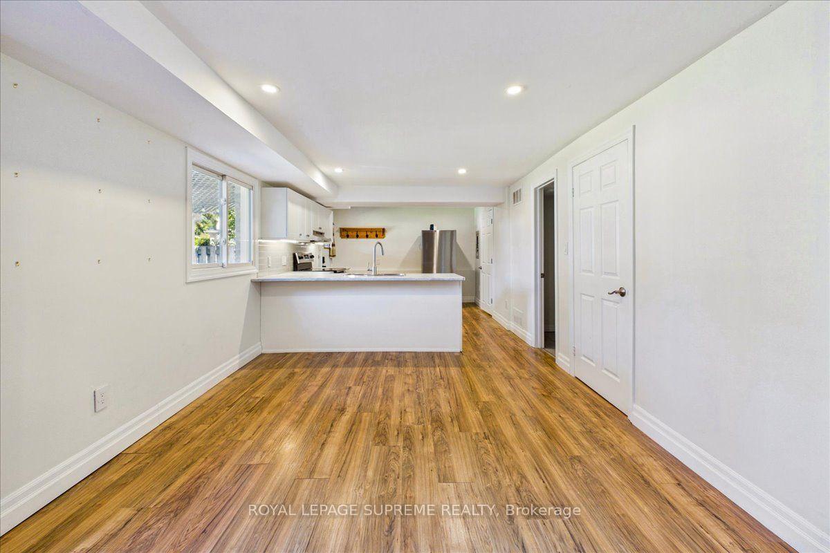 Vacant lower-level kitchen with a peninsula, stainless steel appliances, and warm wood-look flooring.