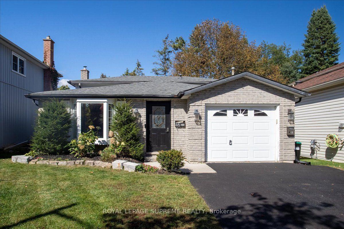 Single-story brick house with a white garage door, dark front door, and landscaped lawn.