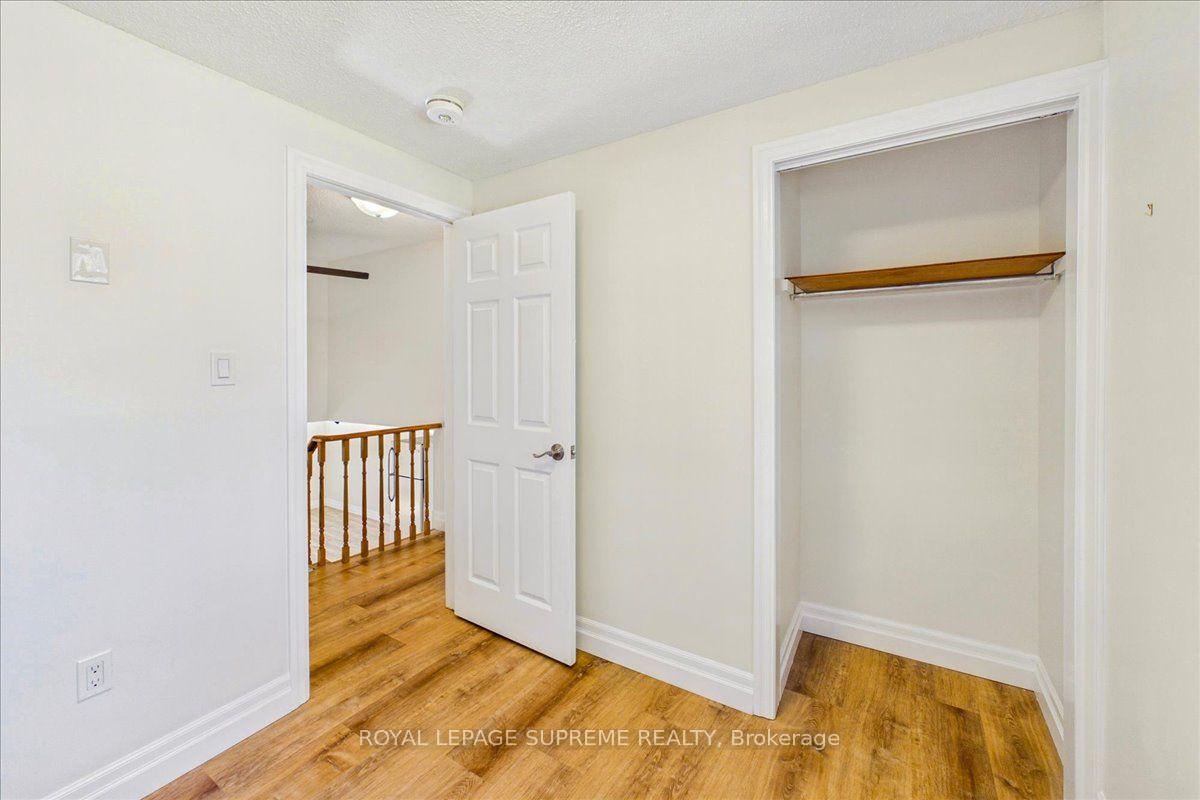 Empty room with wood flooring, an open closet, and a doorway to a landing with a wooden railing.