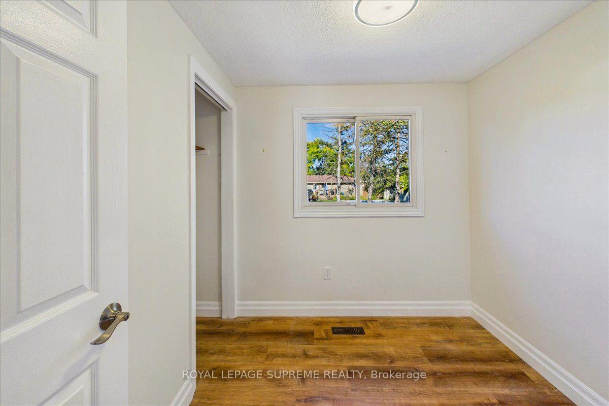 Empty room with warm-toned wood flooring, a window, and an open closet doorway.