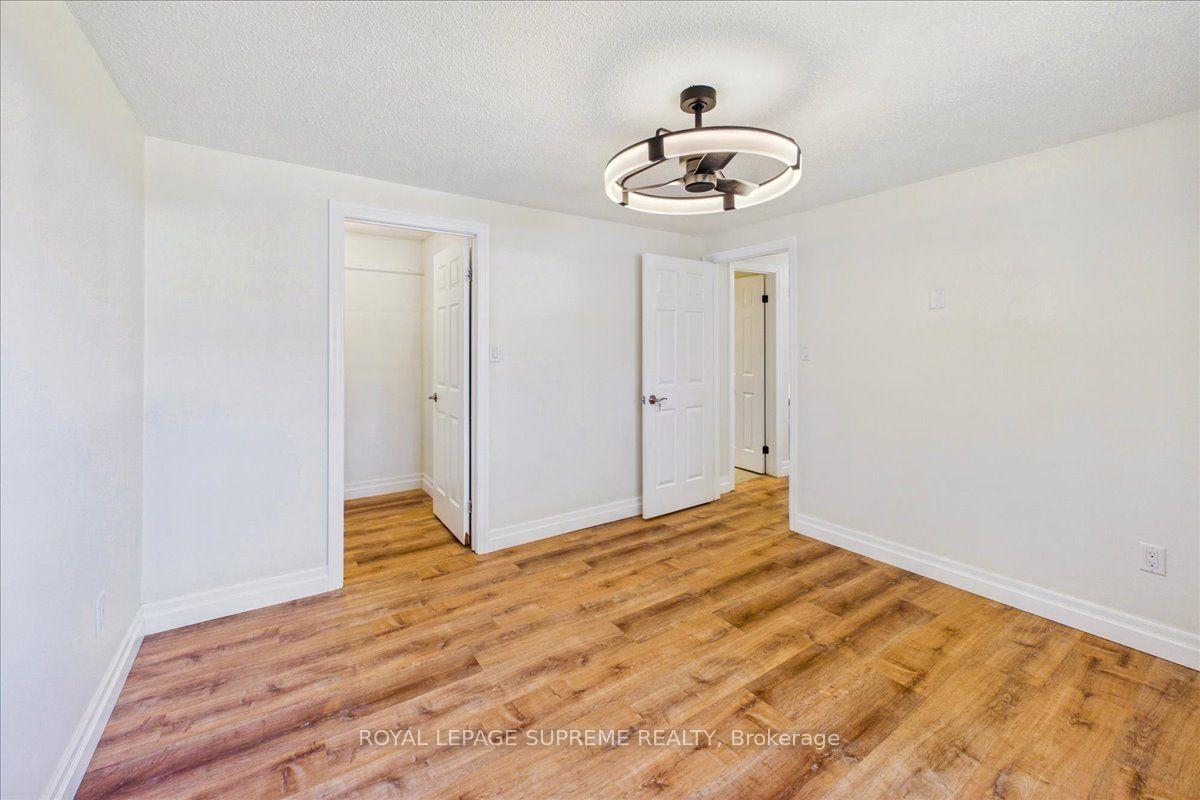 Vacant room with warm wood-look flooring, white walls, and a circular ceiling light.