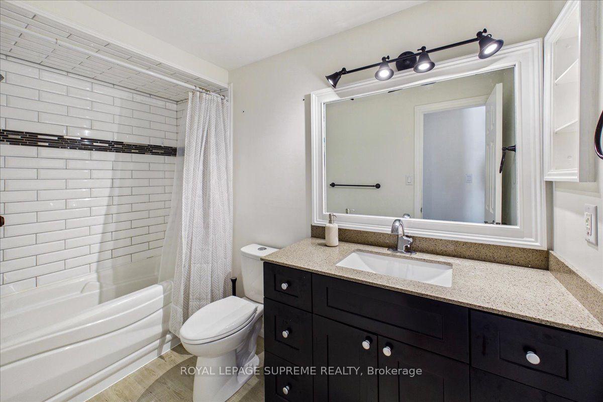 Bathroom with a subway-tile shower, patterned curtain, and dark vanity with a large mirror.