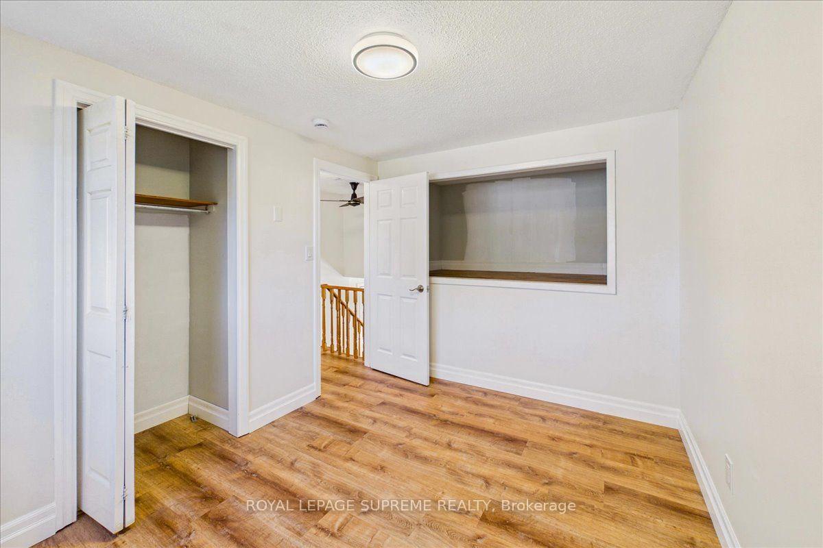 Empty bedroom with wood-look flooring, an open closet, and a wide interior pass-through.