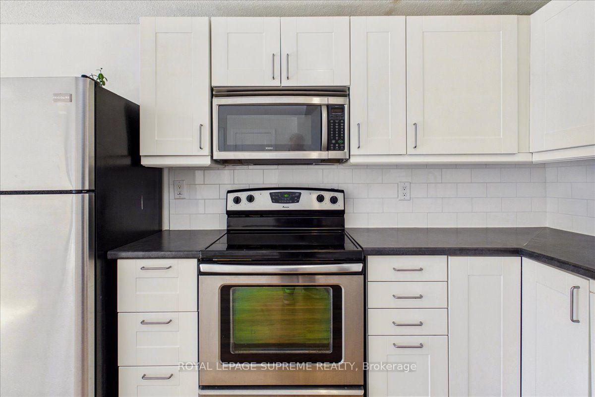 Kitchen with white cabinets, dark countertops, and stainless-steel range and microwave.