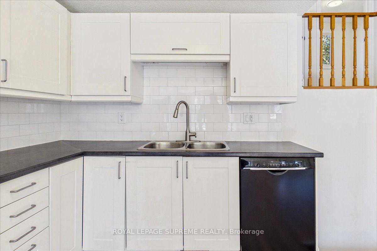 Kitchen with white cabinets, dark countertops, a double sink, and black dishwasher.