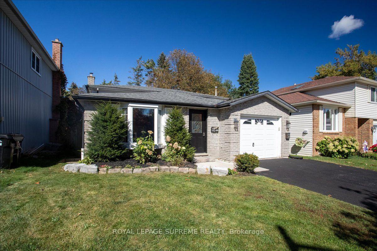 Gray brick house with a white garage door, dark front door, and landscaped front garden.