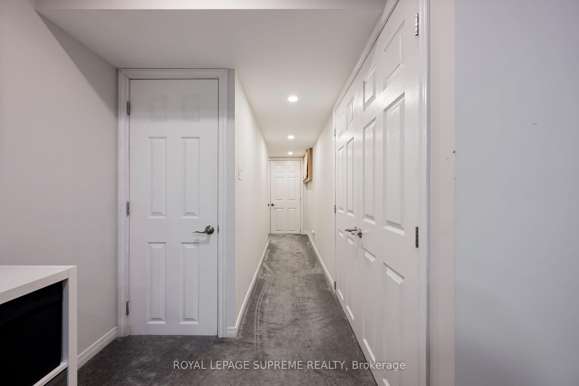 Carpeted hallway with white paneled doors and recessed ceiling lights.