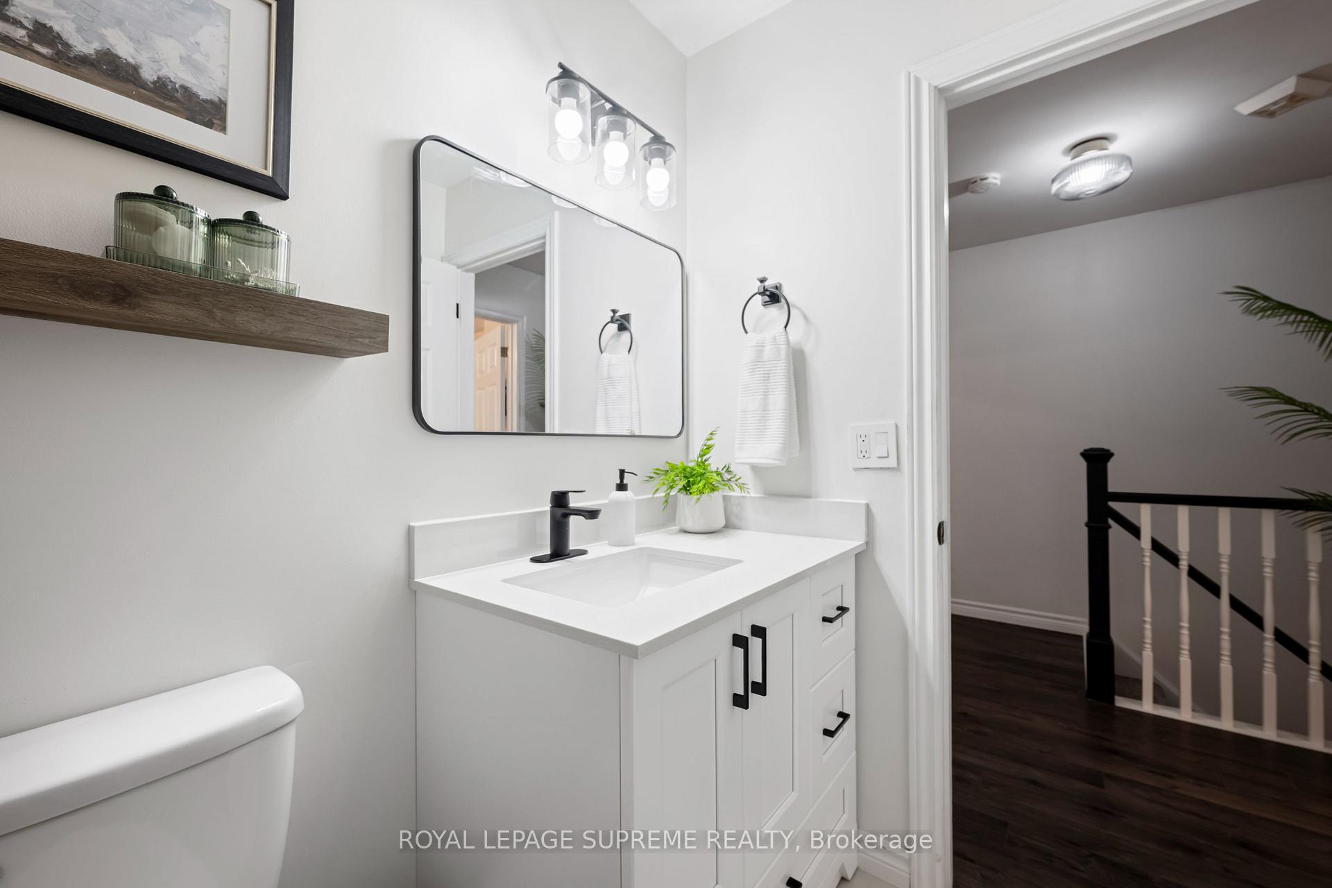 Bright bathroom with a white vanity, black fixtures, and a large mirror beside an open doorway.