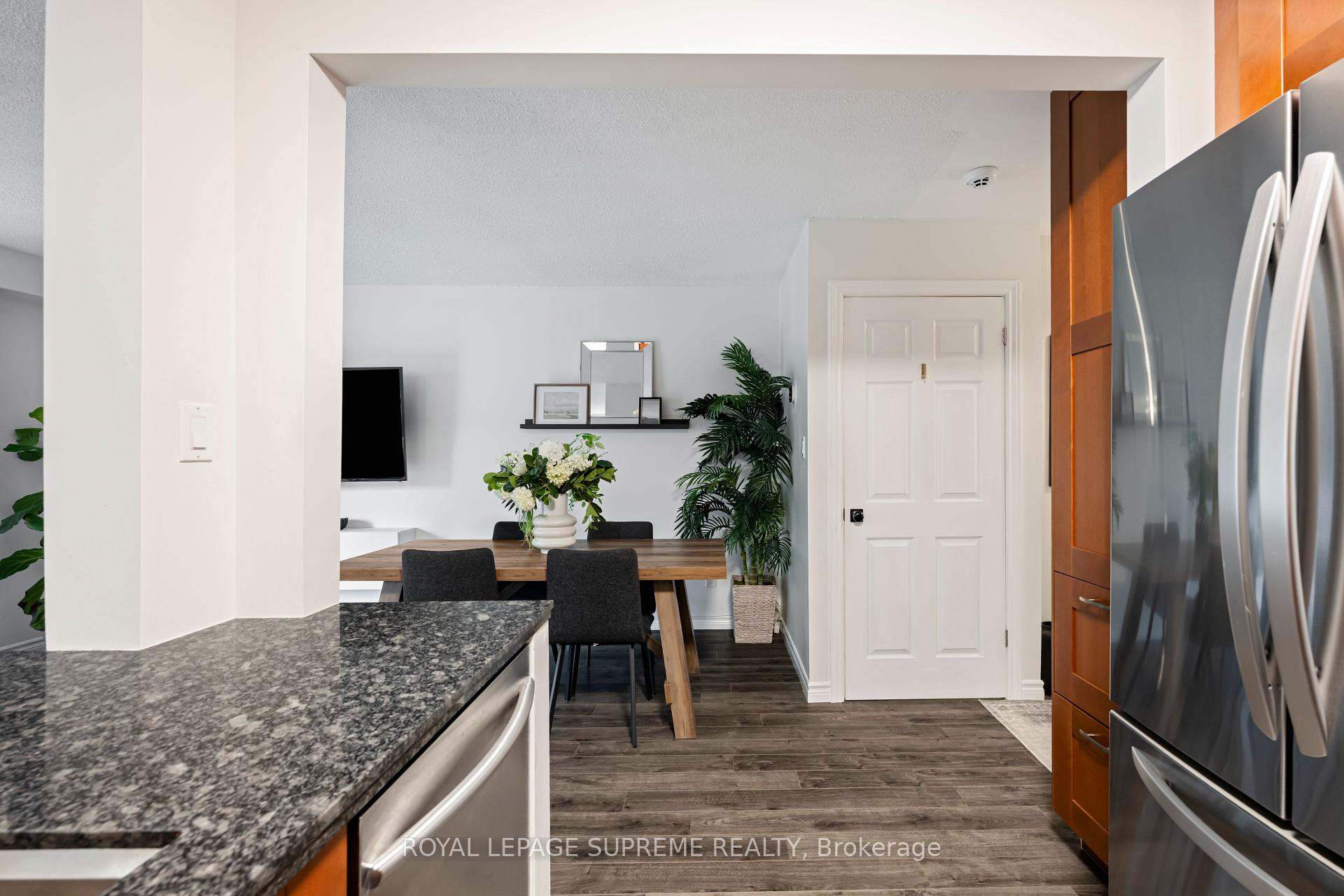 Open kitchen and dining area with a gray stone island, stainless steel appliances, and a wood table.