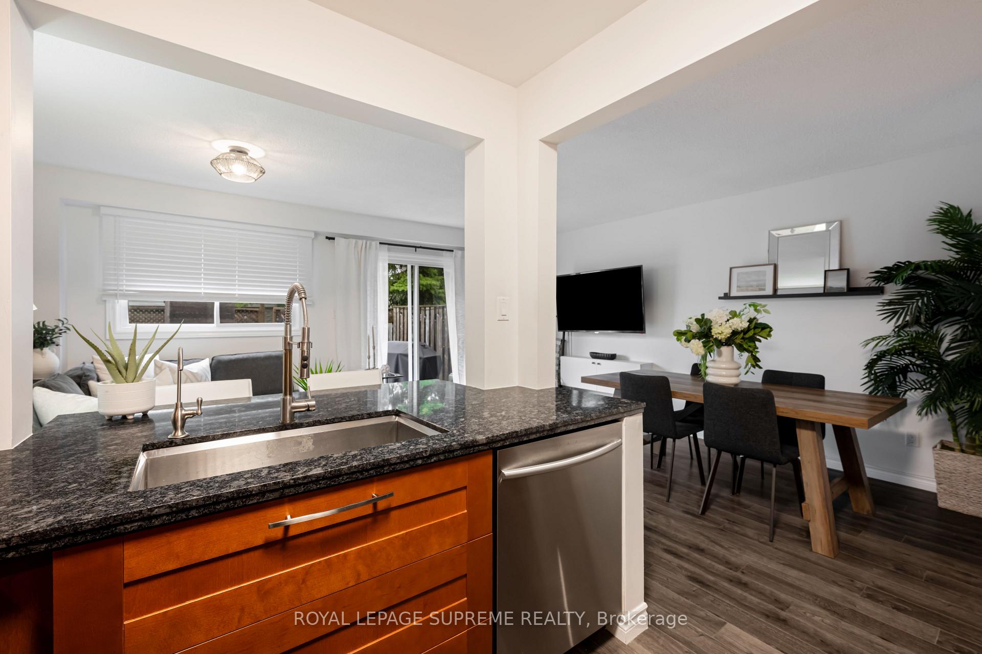 Open-concept kitchen with granite island, stainless-steel appliances, and adjoining dining and living areas.