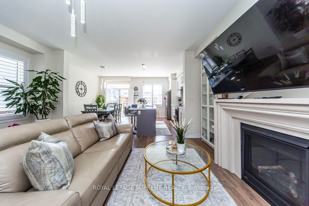 Living room with a beige sectional, glass-and-gold coffee table, fireplace, and open dining area.