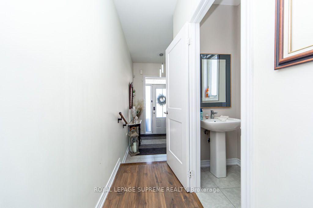 Front entry hallway with wood flooring and an open powder room doorway showing a pedestal sink.
