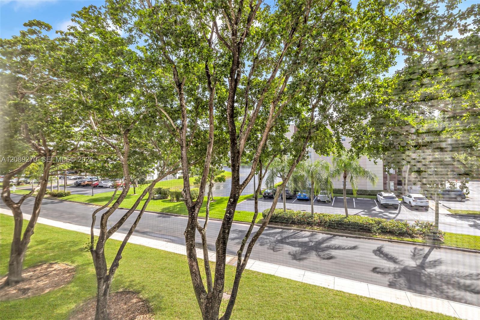 View of leafy grounds, a parking lot, and a residential building from among the trees.