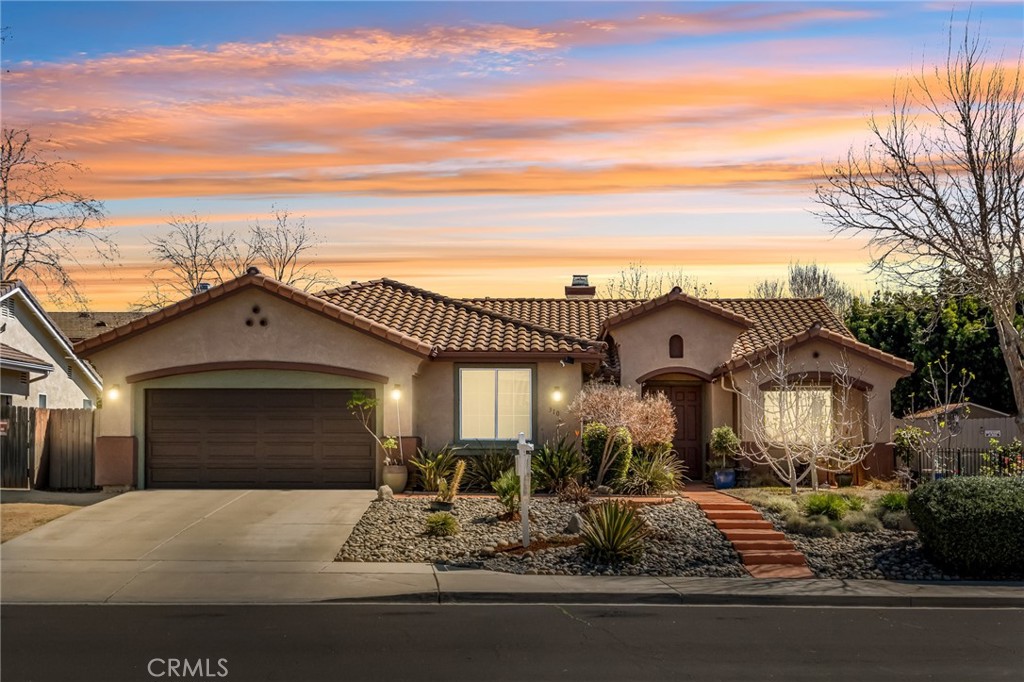 Single-story stucco home with a tiled roof, two-car garage, and drought-tolerant front landscaping.