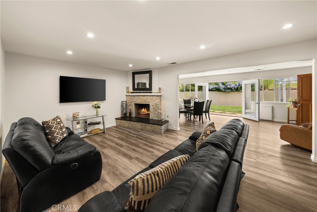 Living room with leather sofas, a stone fireplace, and open doors to the backyard.