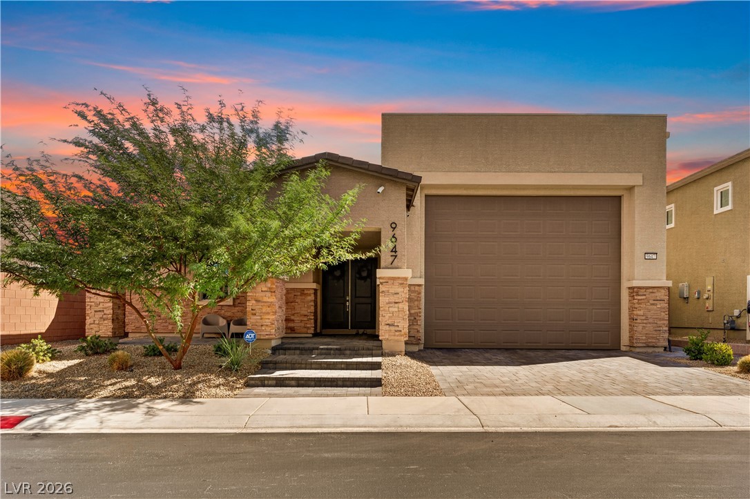 Home exterior with a two-car garage, stone accents, desert landscaping, and address number 9647.