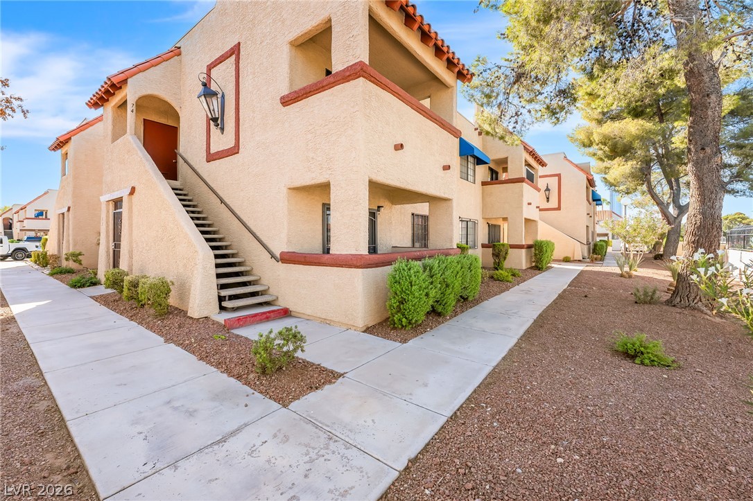 Two-story stucco condominium building with an exterior stairway and desert landscaping.