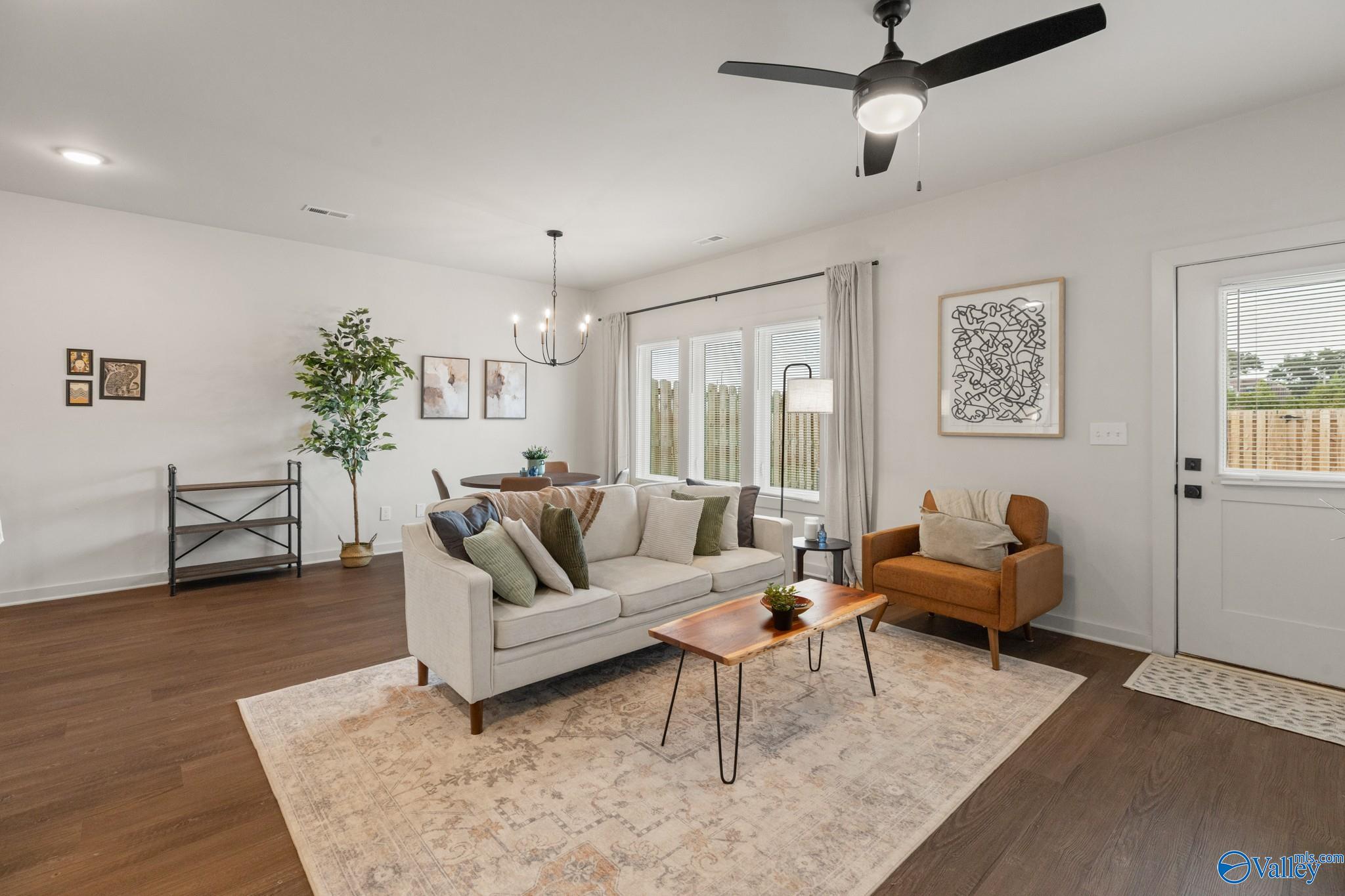 Furnished living room with a cream sofa, rust-colored armchair, and large windows.