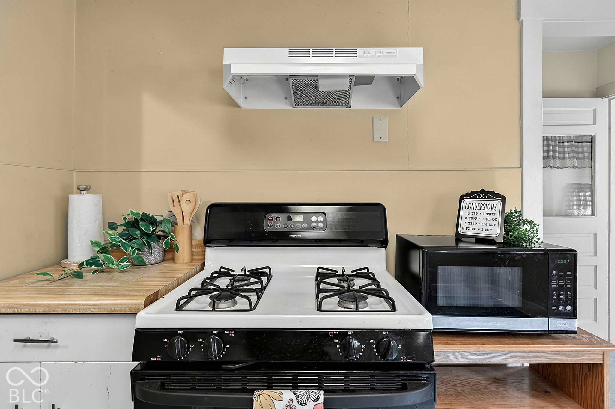Kitchen with a white gas range, wood countertops, and a microwave beside it.