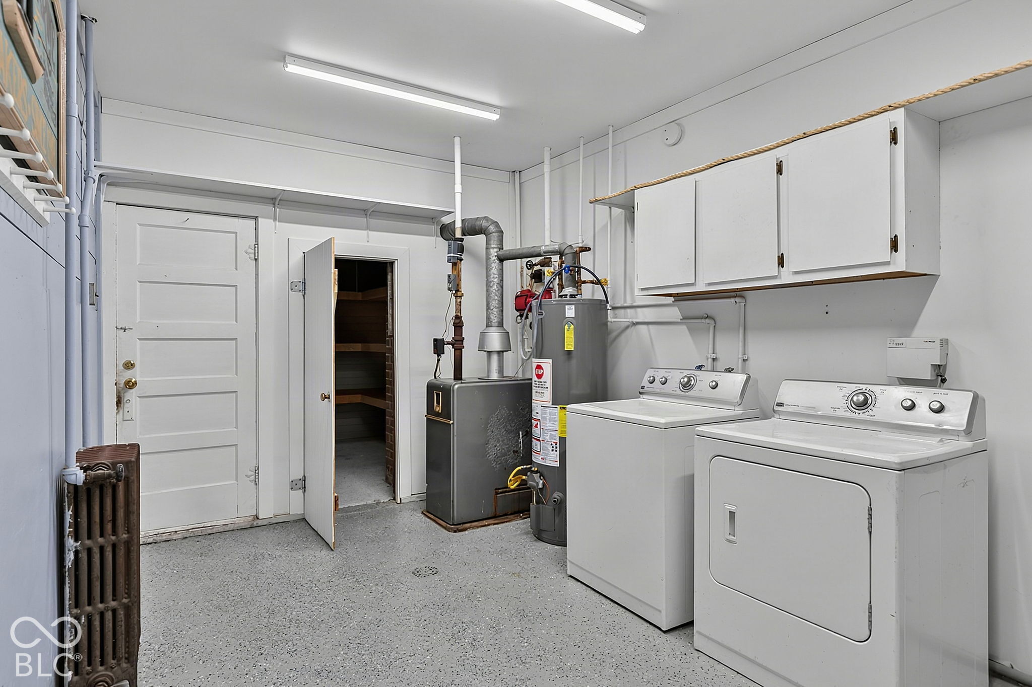 Utility room with washer, dryer, furnace, water heater, and overhead cabinets.