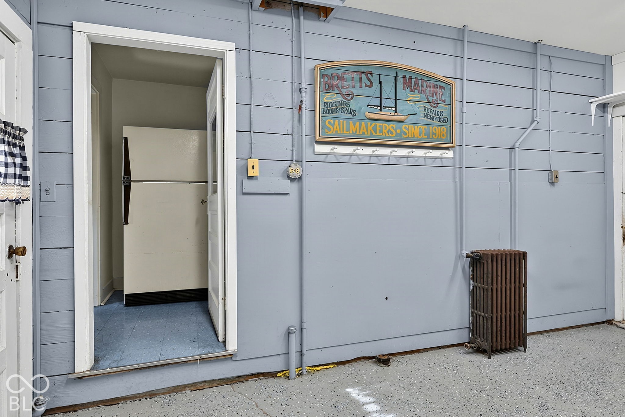 Utilitarian interior with pale blue paneled walls, an open doorway, and a vintage marine sign.