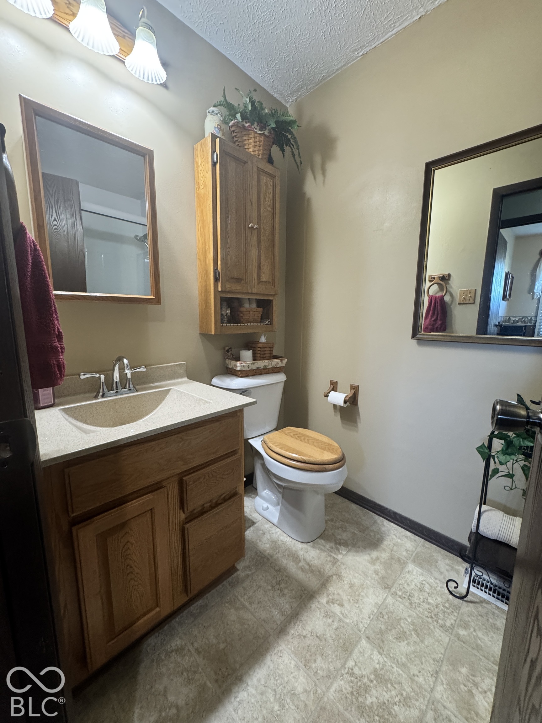 Bathroom with a wood vanity and matching toilet seat, wall cabinet, and tiled floor.