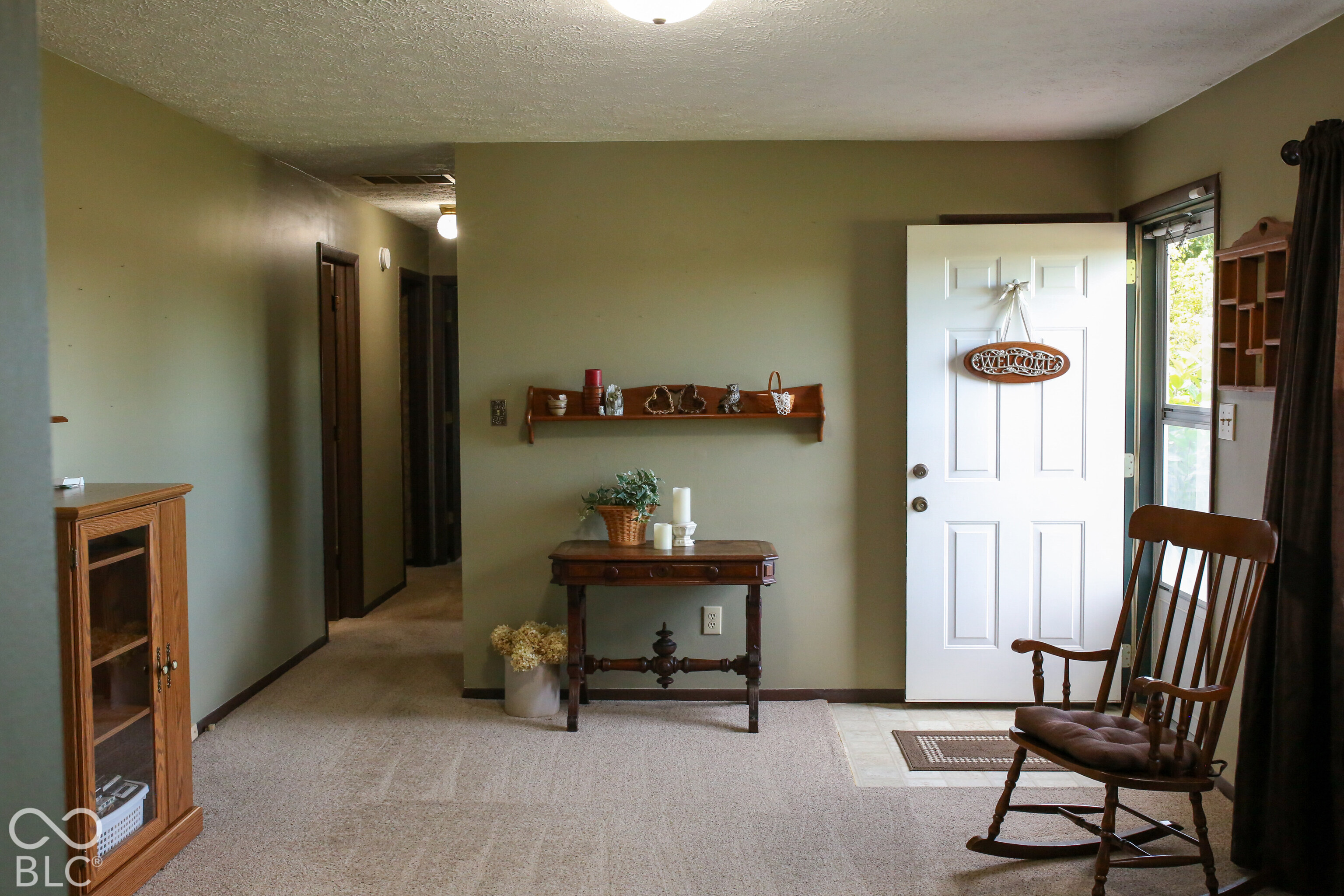 Home entryway with an open white front door, wooden console table, and rocking chair.